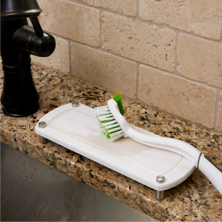White kitchen scrubber with green bristle head on a granite countertop.